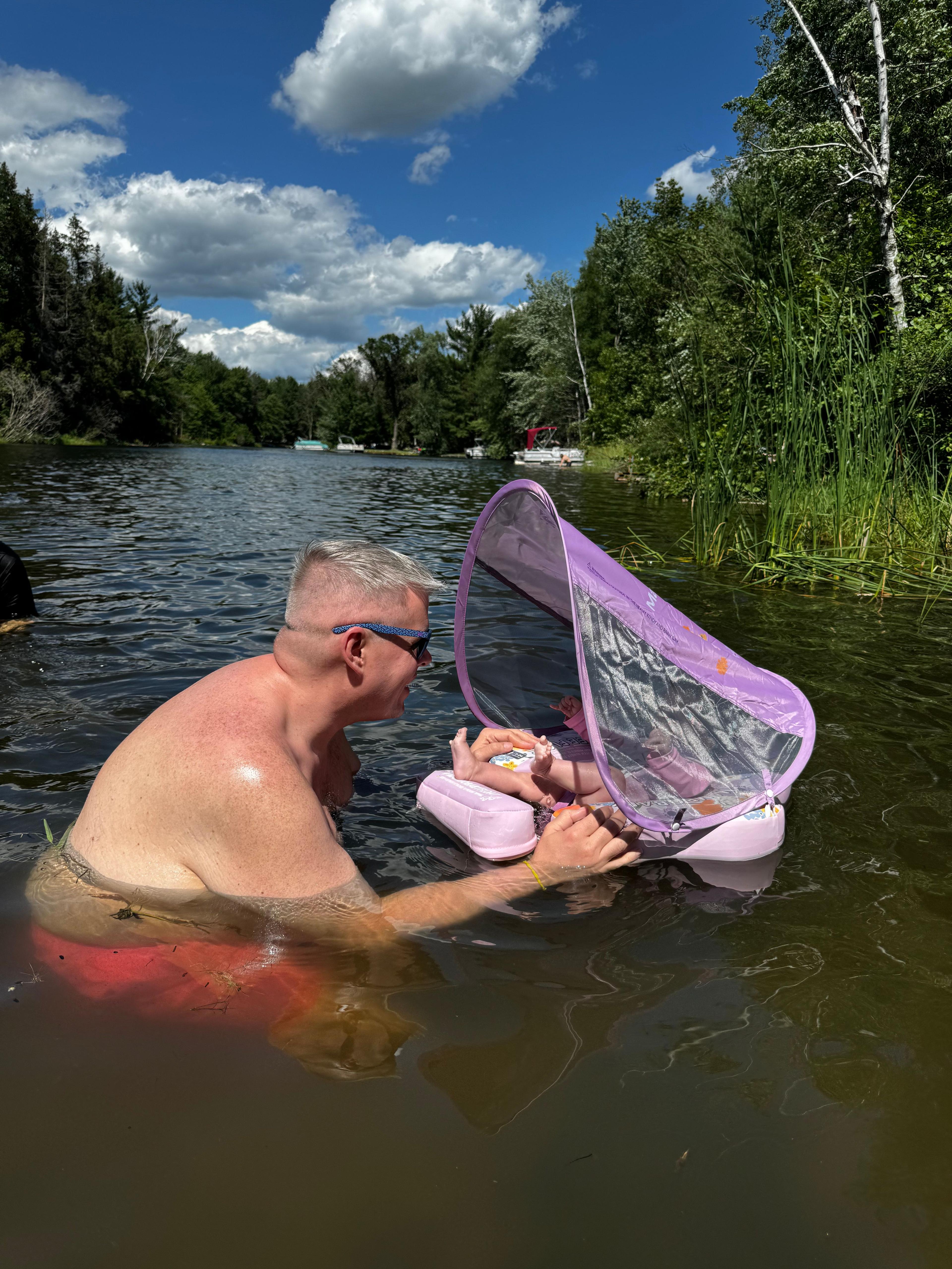 a man in a lake with a baby in a small float