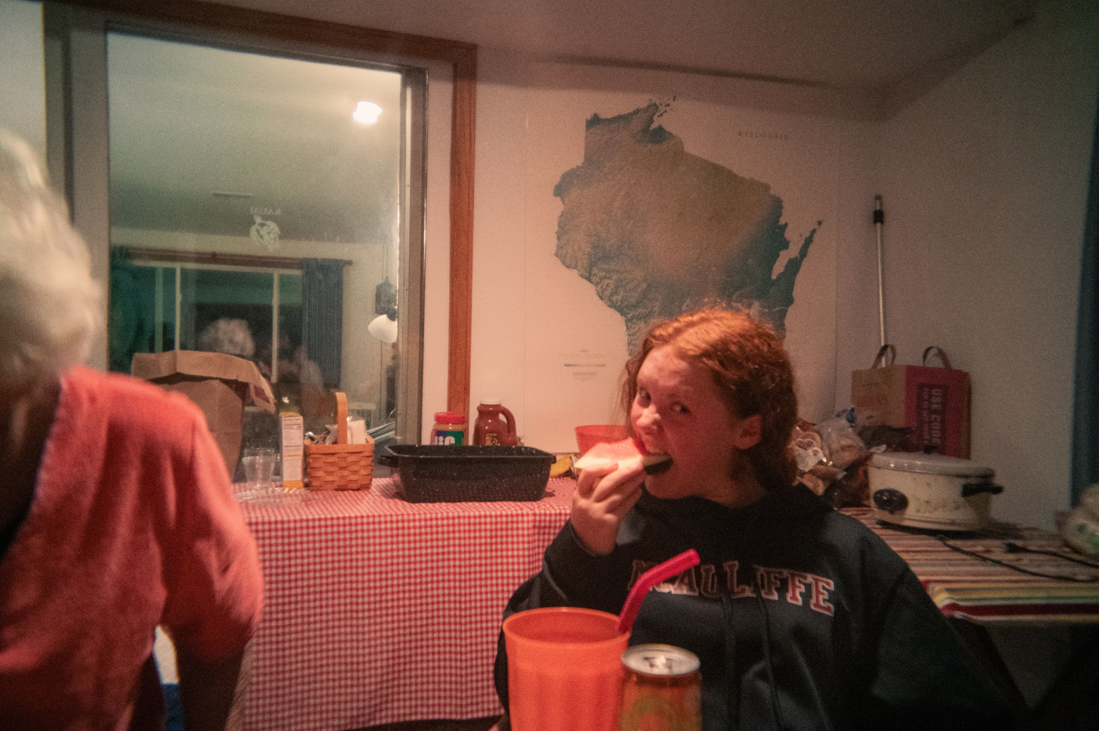 A girl taking a large bite of watermelon