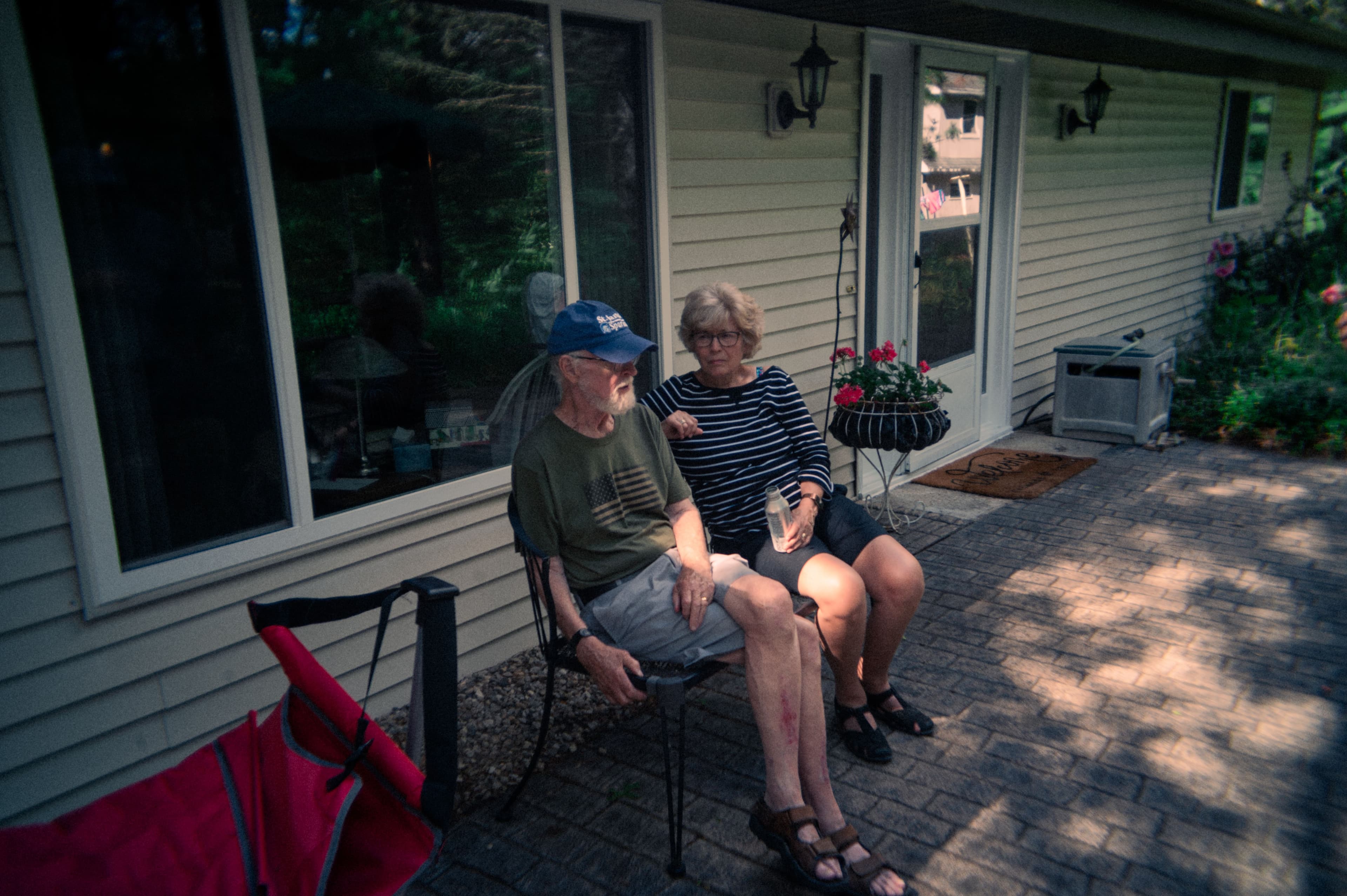 two people sitting on a bench outside a lakehouse