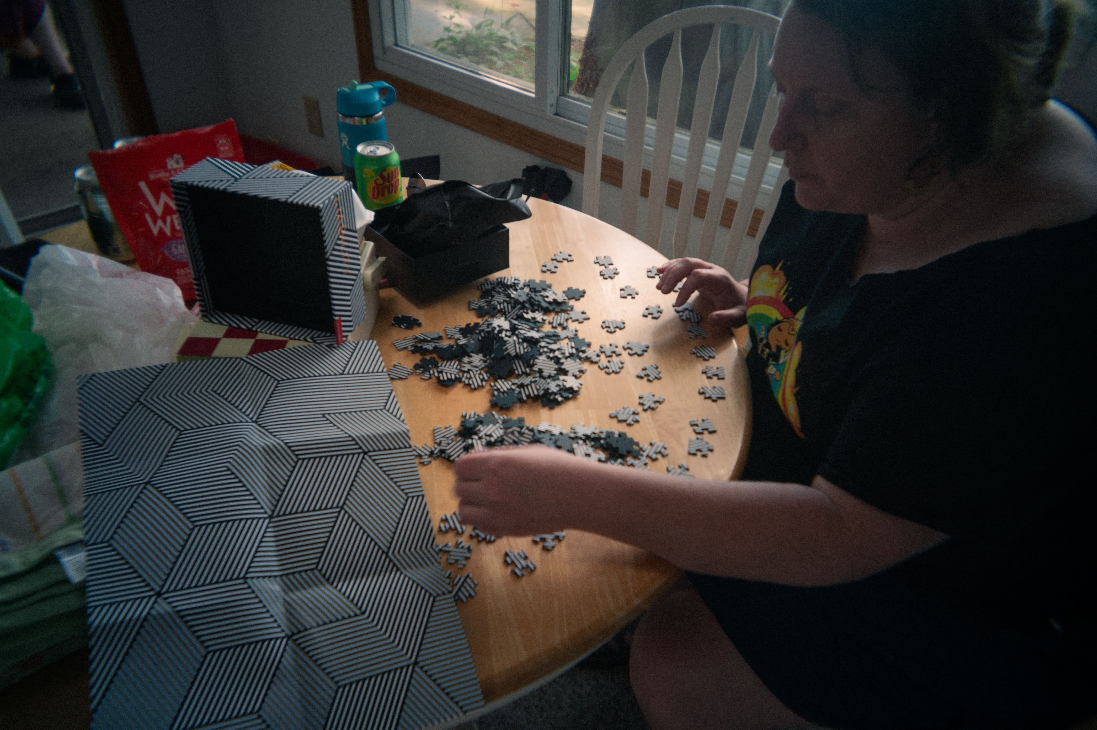 a woman putting together a puzzle at a small table